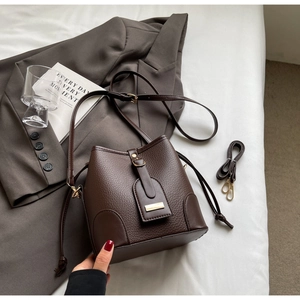 Detail of chocolate brown lychee texture leather bucket bag with gold hardware buckle