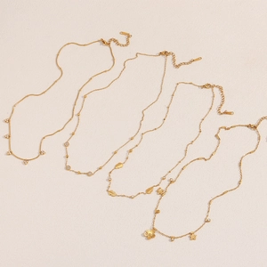 Flat lay of five 18K gold plated stainless steel necklaces with floral and leaf pendants