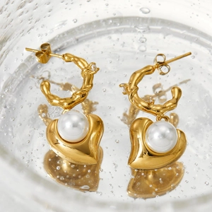 Close-up of golden heart earrings with pearls and lava texture in a bubbly glass water tank