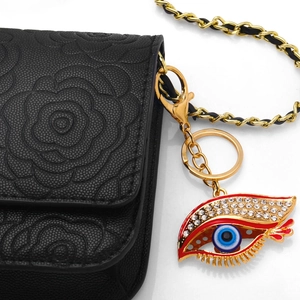 Blue Evil Eye metal keychain with crystals hanging on a black quilted bag chain