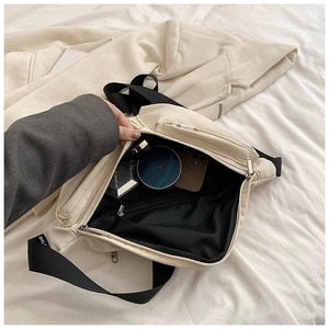 Detail view of cream crossbody bag interior showing spacious compartments and zip pocket