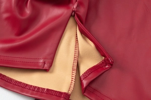 Detailed macro view of red PU leather fabric featuring invisible zipper and tan suede lining