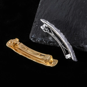 Detail of gold and silver metallic hair clips with crystal inlay on dark stone