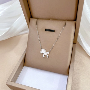 Detail of silver pony pendant necklace in jewelry box with soft fabric background