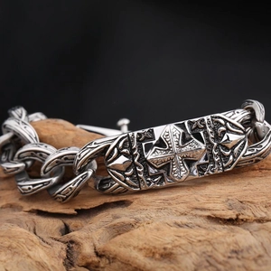 Vintage stainless steel cross bracelet with engraved chain links on rustic wood