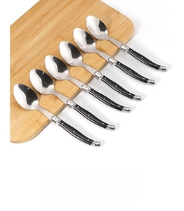 Detailed view of six Laguiole style stainless steel spoons with black riveted handles on wood