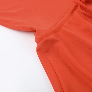 Detailed view of the orange knit fabric with drawstring and fine stitching at the waistline