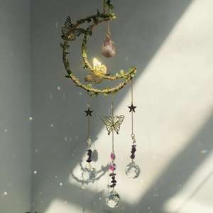 Detail of moon-shaped crystal suncatcher with rope leaves and gold metal butterflies