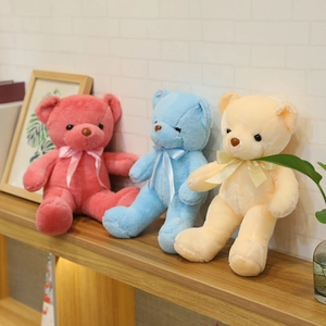 Vista detallada de tres coloridos osos de peluche con lazos en un estante de madera