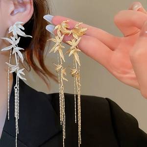 Detail of bamboo leaf tassel earrings on model in gold and silver finishes