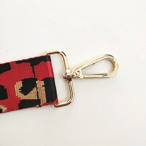 Detailed close-up of leopard print webbing strap with light gold metal swivel hooks