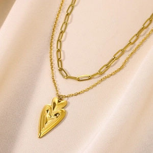 Detail of 18K gold-plated double-layer necklace with a 3D heart pendant on satin background