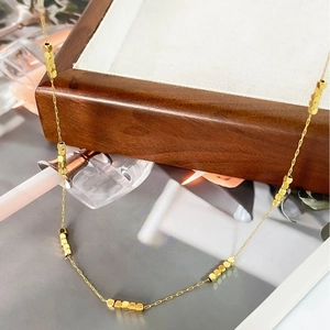 Minimalist 18K gold plated titanium necklace with small hexagonal beads on a wooden box