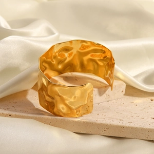 Macro shot of 18K gold plated stainless steel cuff bracelet on stone and silk