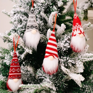 Christmas gnome hanging decorations with knit hats and faux fur on snowy tree