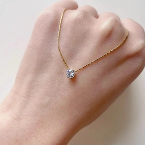 Minimalist gold zircon necklace with round solitaire pendant worn on hand for women
