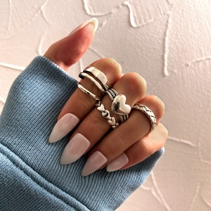 Five-piece silver vintage ring set featuring heart and braided designs on model's fingers