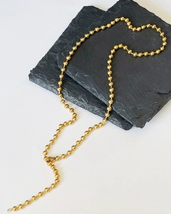 Macro shot of minimalist gold ball chain necklace showing smooth texture and lobster clasp