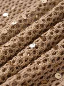 Gros plan sur un tricot kaki avec texture ajourée et détails de paillettes dorées