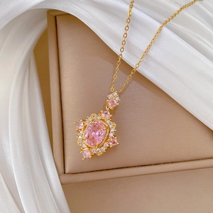 Luxury rose gold necklace with a pink oval gemstone pendant on beige jewelry box