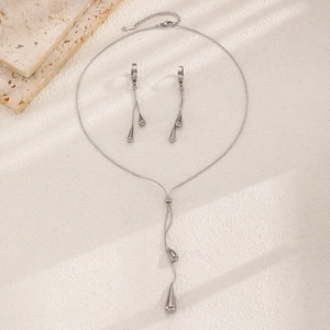 Close-up of silver teardrop pendant necklace and earrings set in polished stainless steel