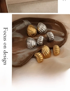Macro detail of vintage textured gold and silver earrings on a brown ceramic plate