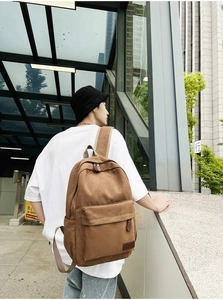 Brown canvas backpack detail featuring padded adjustable straps on a casual male model