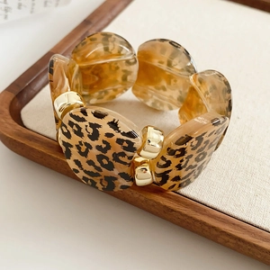 Macro detail of leopard print acrylic discs and gold metal accents on a stylish bracelet