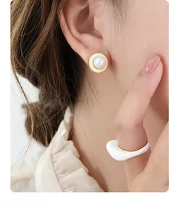 Detail of vintage round pearl earrings and white enamel ring on a female model