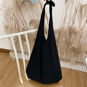 Detail of minimalist black canvas tote bag with adjustable knotted shoulder strap
