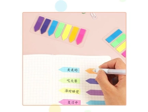 Detailed view of colorful PET arrow index tabs on a grid notebook with stationery