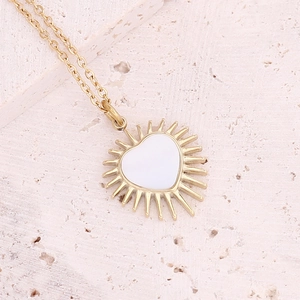 Detailed view of gold stainless steel necklace with white enamel heart pendant on stone