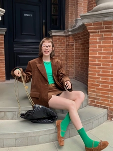 Detail of caramel corduroy blazer and skirt set styled with green knitwear and loafers