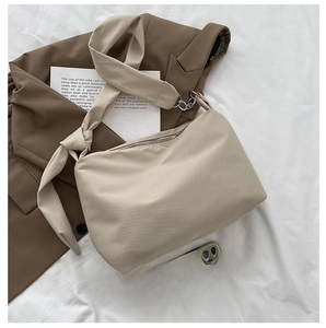 Detail view of beige canvas shoulder bag with knotted strap and metal chain links