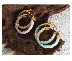 Macro detail of U-shaped gold earrings with purple enamel and inlaid zircons