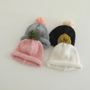 Detail view of colorful knit hats with contrast yarn pom poms in pink grey black and white