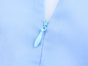 Detail of invisible zipper on light blue dress showing high-quality fabric texture
