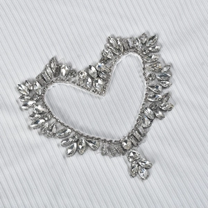 Détail d'un appliqué en strass en forme de cœur sur un crop top blanc côtelé