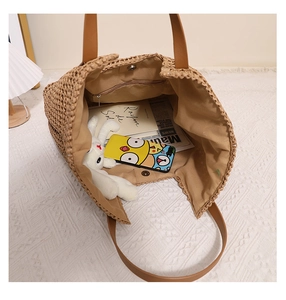 Interior view of straw tote bag with brown leather straps and beige fabric lining