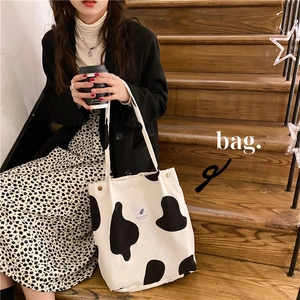 Detail view of large corduroy tote bag with cow print and square patch on stairs