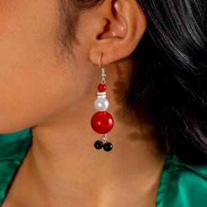 Gros plan d'un mannequin portant des boucles d'oreilles de Noël en perles rouges et blanches