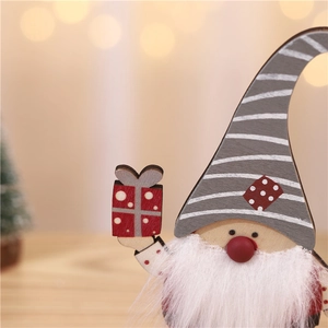 Détail macro d'un gnome de Noël en bois avec bonnet gris et petit cadeau rouge