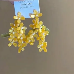 Détail de boucles d'oreilles fleurs jaunes avec tiges en argent 925 et perles