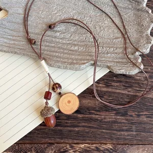 Detailed shot of ethnic necklace featuring acorn pendant and wooden beads on wax cord