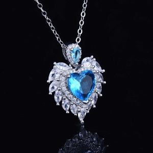 Macro shot of luxury heart-shaped blue gemstone pendant with intricate wing diamond setting