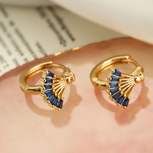 Gold fan-shaped hoop earrings featuring rectangular blue zircon stones on a pink background