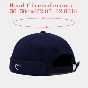 Detail of navy blue skull cap with white heart embroidery and adjustable metal buckle strap