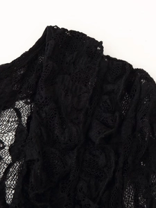 Détail en gros plan de la texture de dentelle noire et des motifs floraux sur la manche