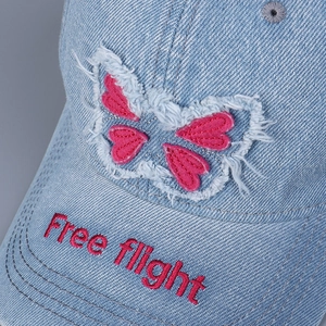 Distressed blue denim baseball cap featuring bow embroidery and Free Flight brim text