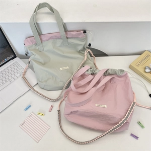 Close-up of contrasting color drawstring tote bags in pink and sage green fabric